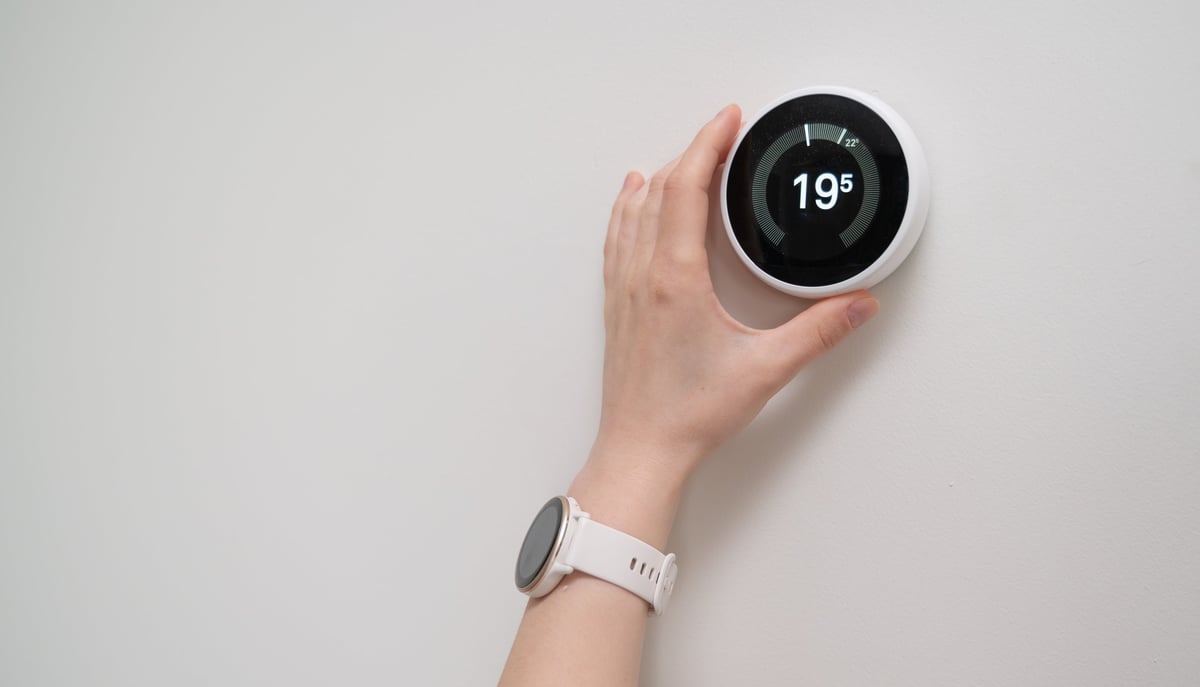 A hand adjusting a smart thermostat for energy efficiency