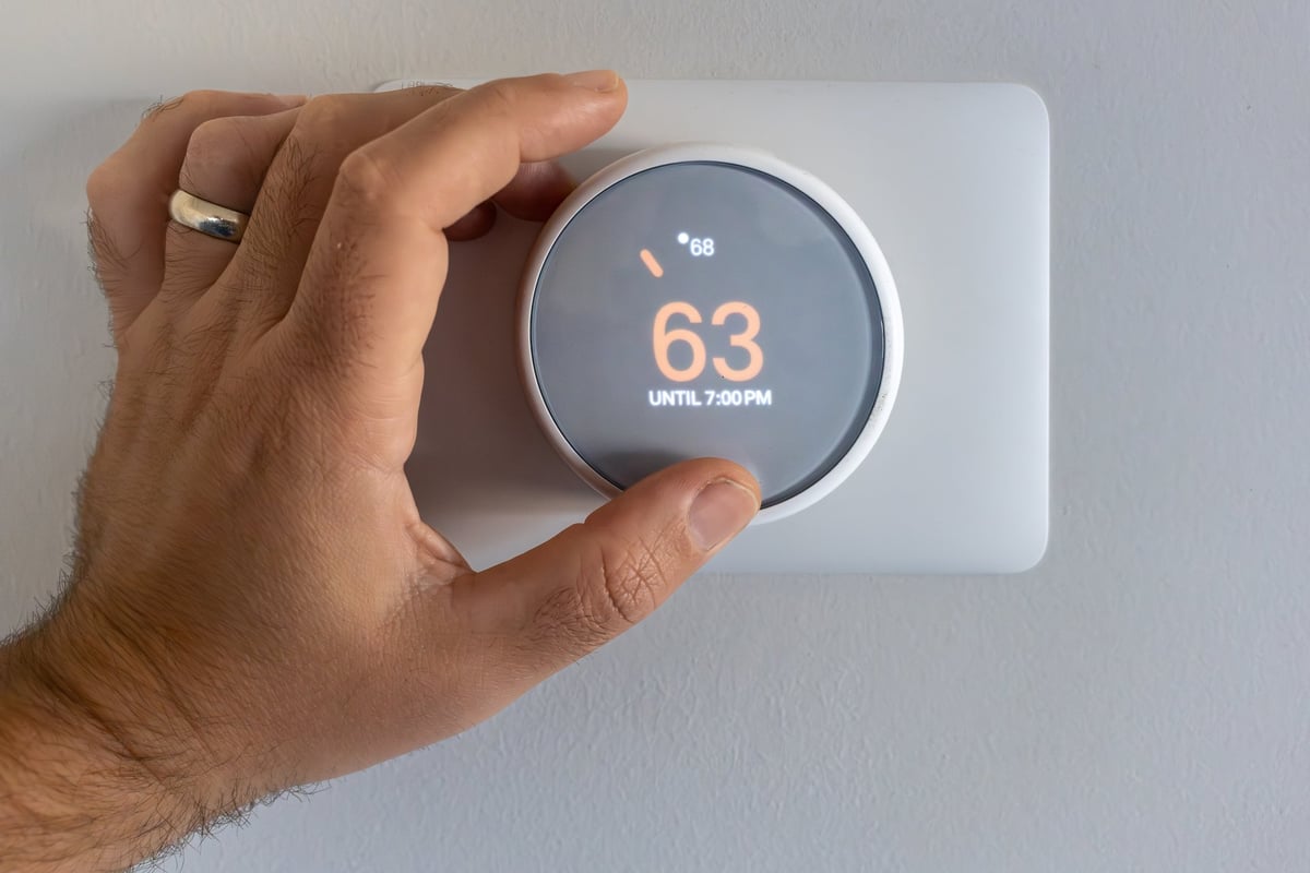 Homeowner adjusts a smart thermostat